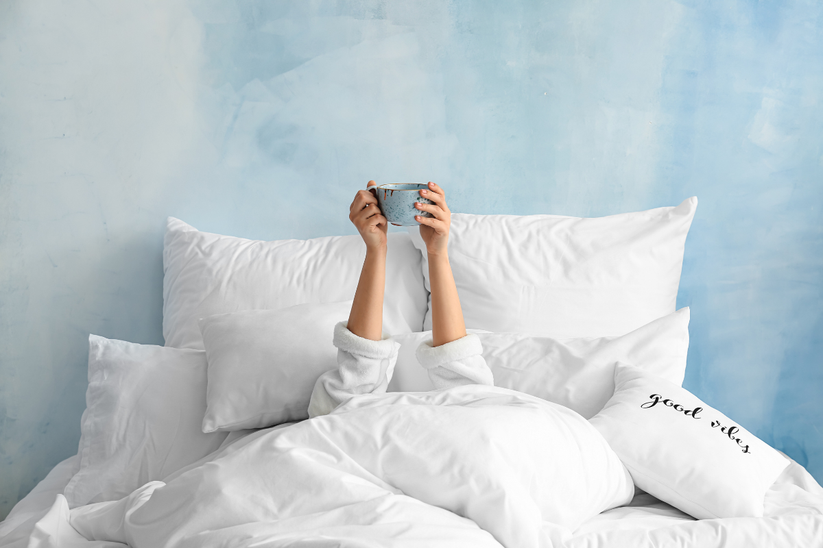 Lady holding cup up in bed