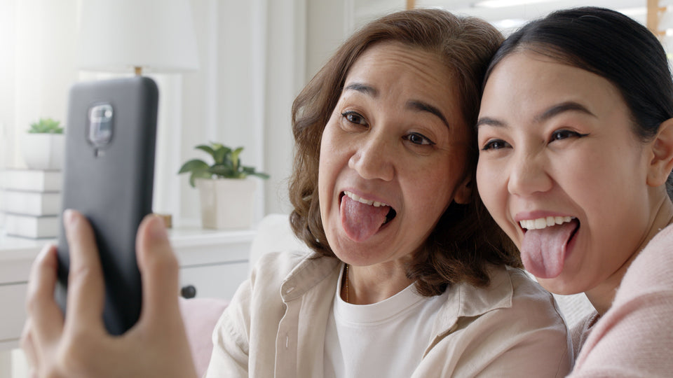 Mother and daughter taking a funny selfie sticking their tongues out while learning simple mouth exercises to reduce snoring.