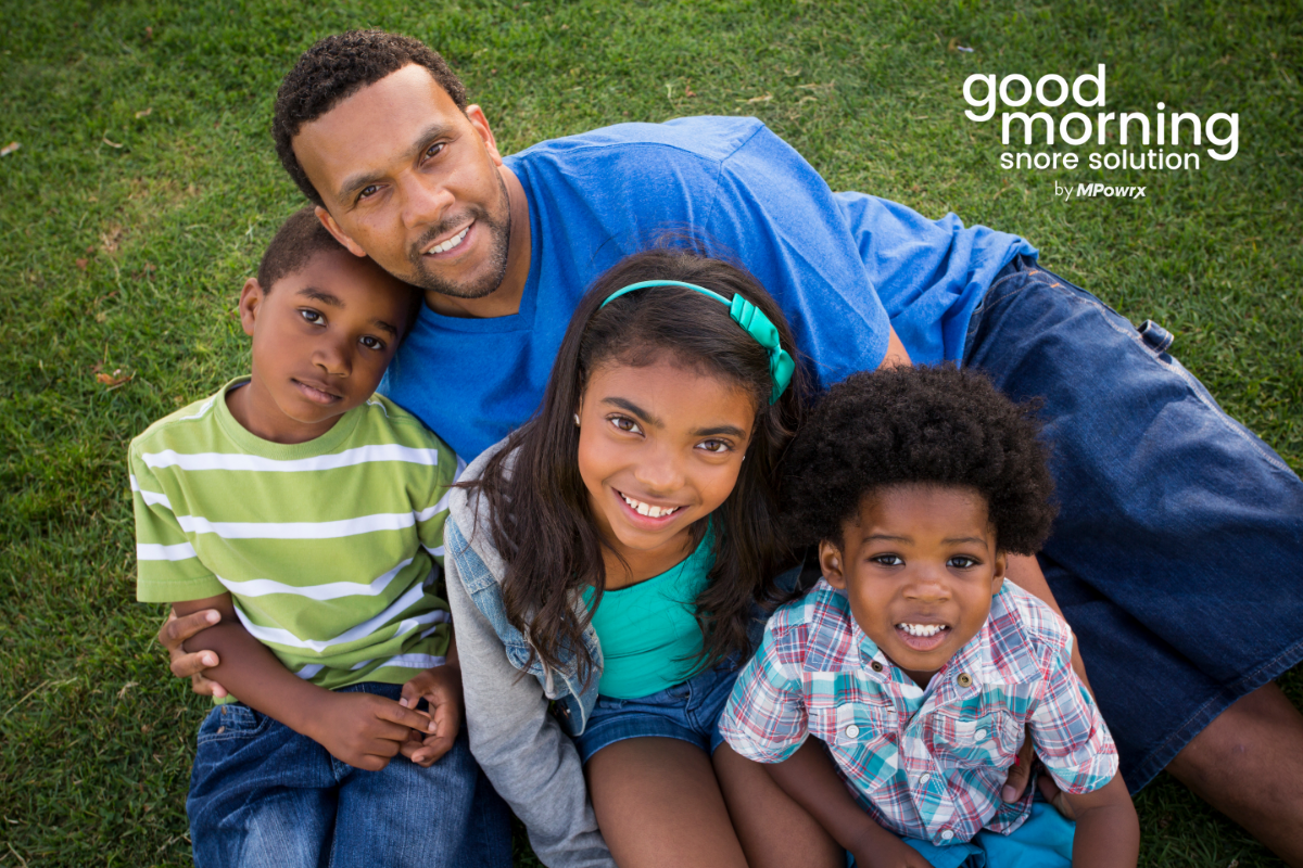 Father, hugging three kids outside on grass