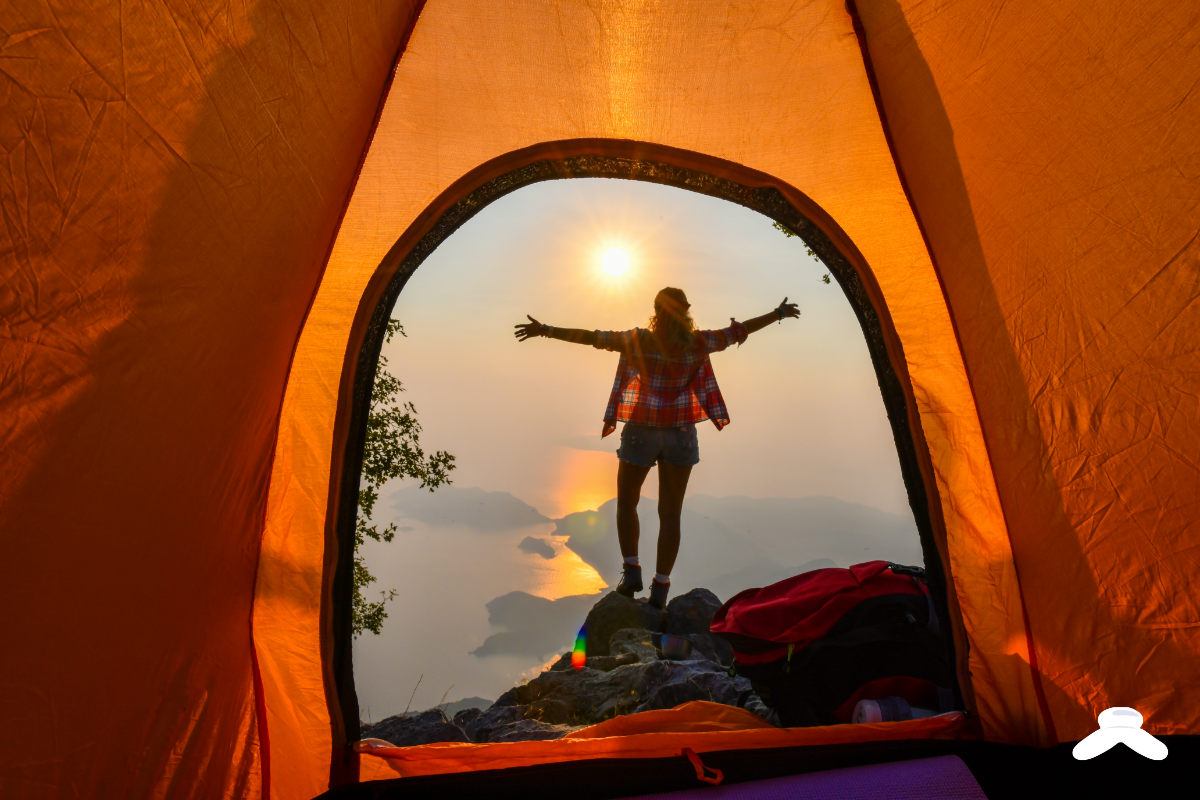 Person camping at sunset with tent