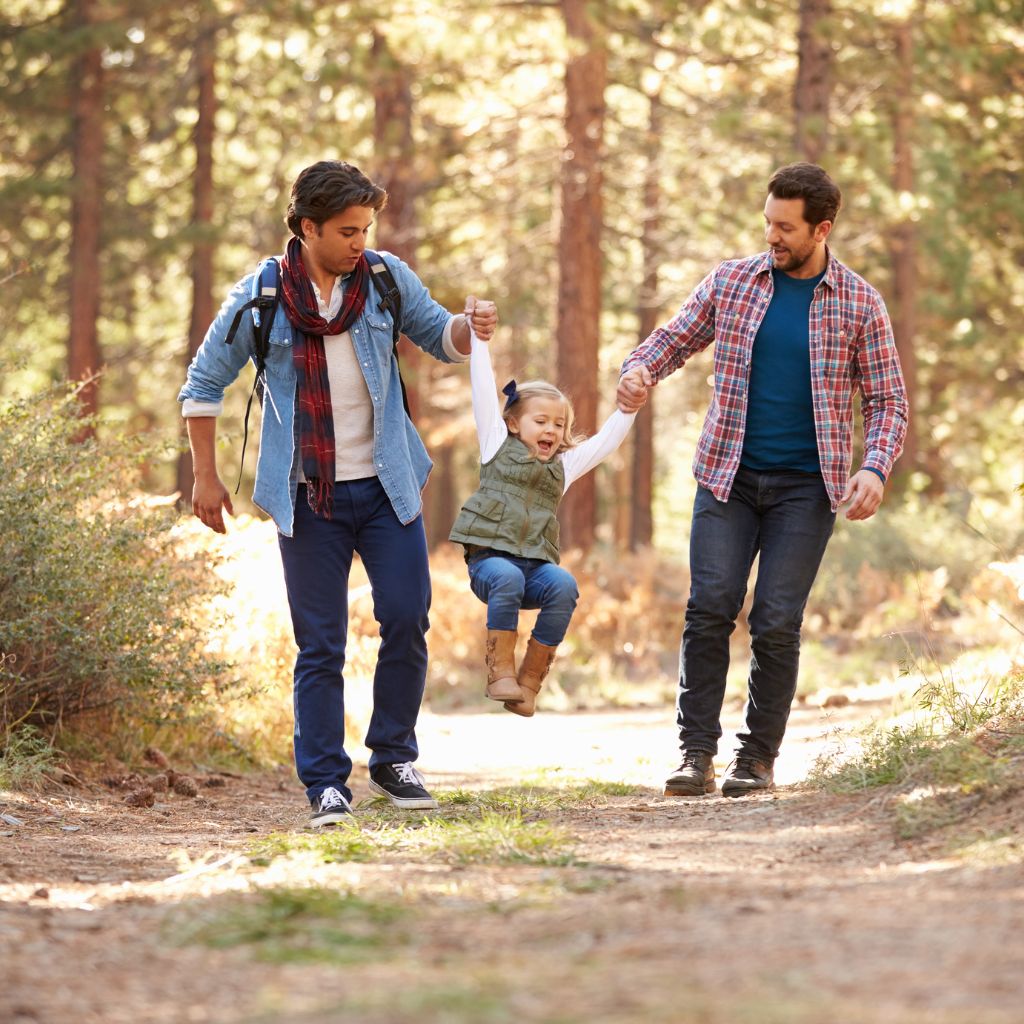 two men walking with a child in center on forest path